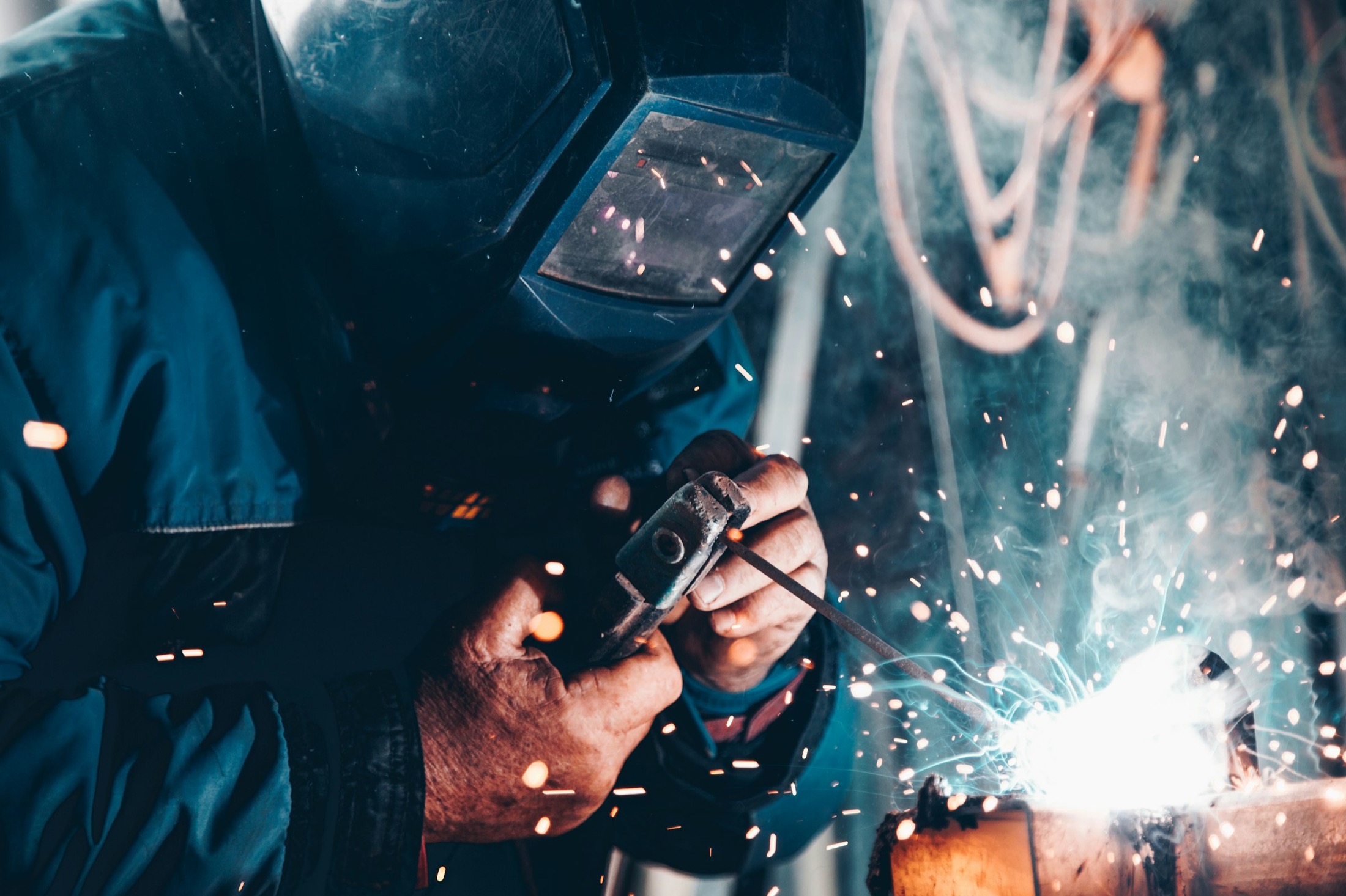 Hands welding in a workshop — systems built by hand